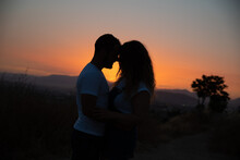 Silhouette Of The Couple Against The Sky At Sunset.