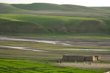 Boys Play Soccer On A Bare Patch Of Ground, Beside A River And Below Hills Brushed With Spring Green, In The District Headquarte