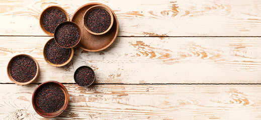 Bowls of healthy quinoa on light wooden background with space for text