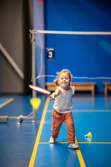 Little girl three years old playing badminton in sport wear on indoor court 