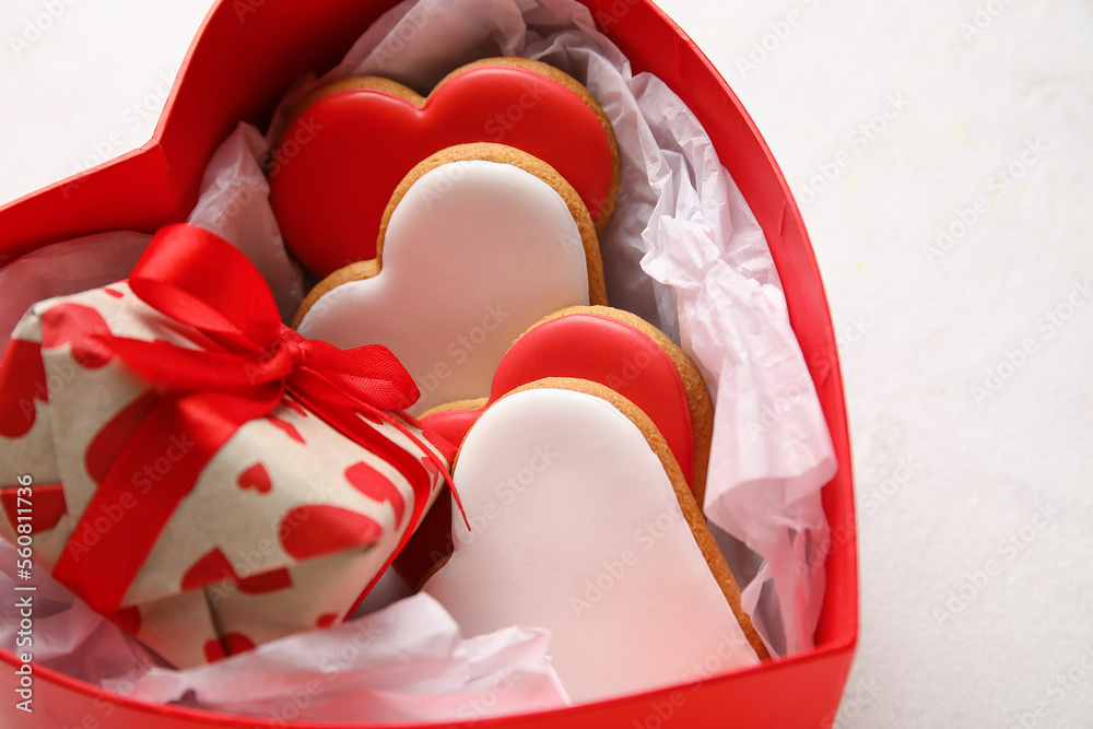 Box with tasty cookies and gift on light background, closeup. Valentines Day celebration
