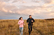 © alfa27 - Young Couple Running On Field In Morning. Caucasian Man And Woman On Jogging Workout, In Sports Clothes. Male And Female Exercising, Training Together, Lead Healthy Lifestyle. Fitness Concept