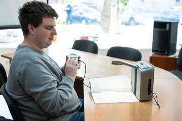 A visually impaired man uses a scanning and reading machine.