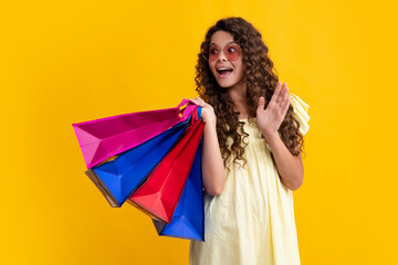 Poster - Amazed teenager. Child girl hold shopping bag enjoying sale isolated on yellow background. Portrait of teenager girl is ready to go shopping. Excited teen girl.