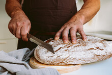 Male Baker At Home Kitchen Cutting Bread