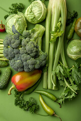 Wall Mural - green fresh vegetables on green background flat lay top view, close-up shot. Seasoning for dish, spices for cooking, bell pepper, broccoli, cucumber, cabbage and other food. Creative layout