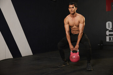 Wall Mural - athletic young man training with kettlebell in the gym