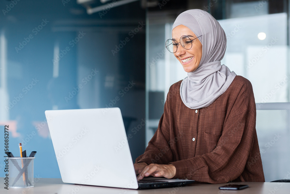 Young beautiful muslim woman in hijab working inside modern office ...