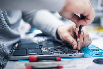 Technical support and fixing gadgets problems. Servicing, repairing, cleaning, maintaining computers. Repair shop. Hardware maintenance. Male technicians fixing disassembled laptop parts.