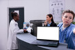 © DC Studio - Laptop computer with white isolated screen standing on hospital counter desk during checkup visit appointment. Physician doctor discussing medical expertise with receptionist, medicine concept