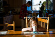 © Cavan Images - Daughter drinking tea on table while father working in background at home