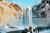 Dreamy looking Skogafoss waterfall in winter with rainbow and people
