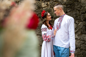 Wall Mural - Portrait of a happy young couple in love, a family hugging, holding hands in the city of Lviv in traditional Ukrainian shirts, holding hands. Young people hug in the old town of Lviv