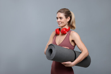 Sticker - Sportswoman with headphones and fitness mat on grey background, space for text