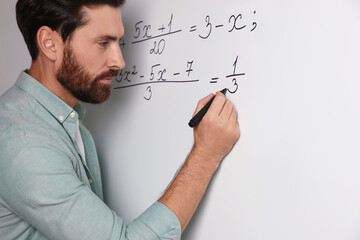Wall Mural - Mature teacher explaining mathematics at whiteboard in classroom, closeup
