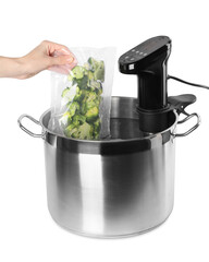  Woman putting vacuum packed broccoli into pot with sous vide cooker on white background, closeup. Thermal immersion circulator