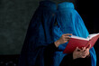 Two Afghan Muslim women with burka traditional costume, reading holy Quran against the dark background