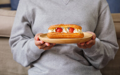 Wall Mural - Closeup image of a woman holding a plate of strawberry Eclair