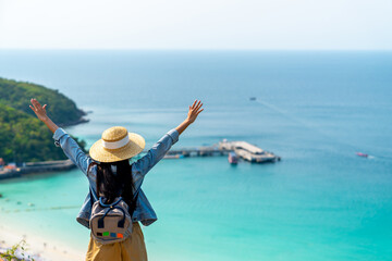 Wall Mural - Attractive Asian woman enjoy and fun outdoor lifestyle looking beautiful nature of ocean and raise hands up during travel on tropical island mountain peak in summer beach holiday vacation.