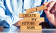 © Uuganbayar - Closeup on businessman holding a wooden block with 'I create my future now'