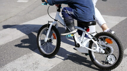 Child crossing street in city crosswalk with mother outdoors