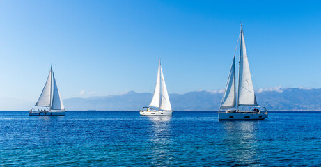 sailing yacht boats with white sails in blue sea , seascape of beautiful ships in sea gulf with mountain coast on background