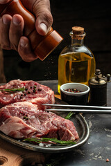 Canvas Print - Pork steak and salt by the chef. Backstage of preparing grilled pork meat. Culinary, cooking concept. place for text