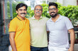 © GAJENDRRA BHATI  - Happy indian senior father standing with his two young sons smiling looking at camera.