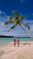 Wall Mural - couple on a tropical beach during vacation at the Island of Koh Kood in Thailand, men and women on a white beach with palm trees. 