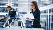 © Gorodenkoff - Portrait of a Young Robotics Engineer Using Laptop Computer, Analyzing Robotic Machine Concept in a High Tech Factory. Female Scientist Manipulate and Program the Robot for Work.