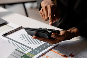 Poster - Businessman using a calculator to calculate numbers on a company's financial documents, he is analyzing historical financial data to plan how to grow the company. Financial concept.