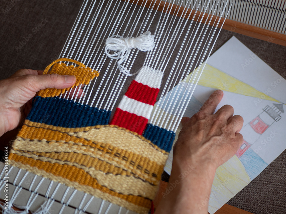 Artisan is checking tapestry against pattern. Tapestry weaving process. Concept of craftsmanship, handmade work