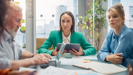 Leinwandbilder - At a Meeting, Team of Entrepreneurs and Specialists sitting at the Conference Table Discussing about Statistics and Charts, Solving Problems, Led by Female Team Lead. They are Using Laptop and Tablet