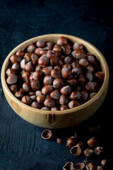 Wall Mural - Hazelnuts in wooden bowl on dark background.