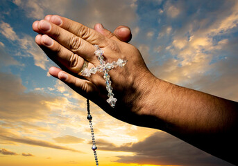 Poster - Man hands in sign of prayer with rosary on sky background