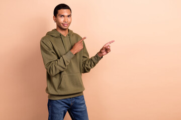 Sticker - Photo of student guy young man wear khaki sportswear hoodie direct fingers mockup opening new shop advert isolated on beige color background