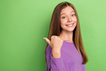 Poster - Portrait of good mood cute girl with long hairstyle wear purple long sleeve directing empty space isolated on green color background