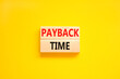 Payback time symbol. Concept words Payback time on wooden blocks. Beautiful yellow table yellow background. Business and payback time concept. Copy space.