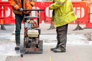 Builder using petrol powered road saw with dimond blade to cut asphalte road surface