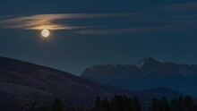 Full moon rising over mount Krivan peak - Slovak symbol - forest trees silhouettes in foreground, evening scene timelapse video