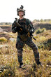 © Roman - young middle-aged soldier in Woodland military uniform and cap, with headphones on head holding rifle. confident motivated military person posing at camera alone outdoors