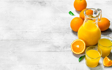 Wall Mural - Orange juice in glass pitcher and fresh oranges.