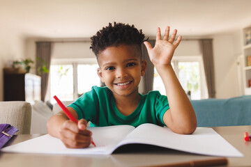 Happy african american boy sitting at table, having online lesson