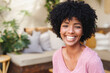 © Wavebreak Media - Close-up portrait of smiling biracial young woman with afro hair sitting in living room