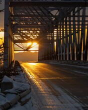 Sunrise In Alaska Sun Shining Through Old Iron Suspension Bridge On Road