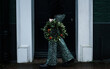© Cavan Images - Woman holding Christmas wreath with sparkly trousers on