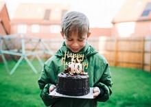 Boy Happily Holding His 10th Birthday Cake With Candles At Home