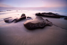 A California Beach With Eroded Rocks At Sunset.