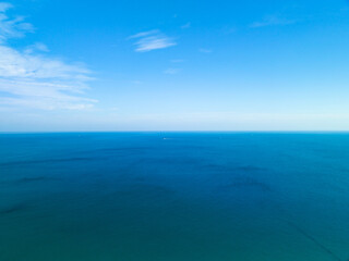 amazing white clouds with blue sky over calm sea and sunlight reflection, aerial view open sea ocean