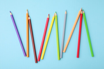 Poster - Colorful wooden pencils on light blue background, flat lay